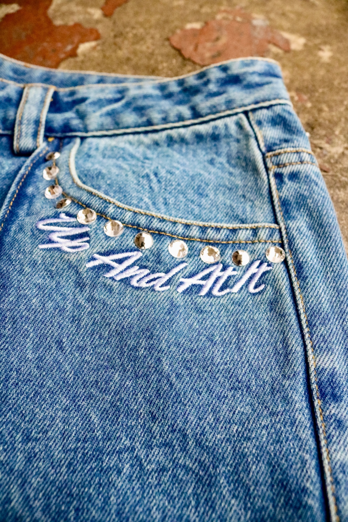 Up And At It script embroidery with rhinestone studs on denim